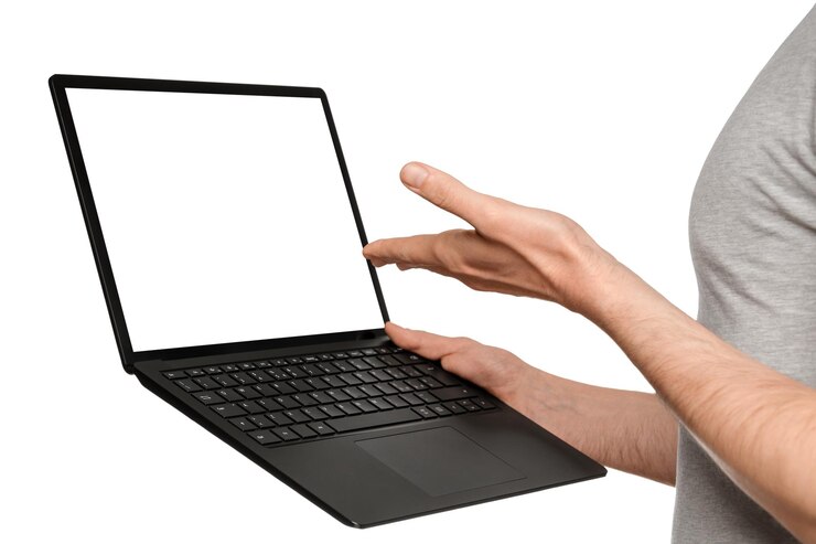 Foto un hombre en una camiseta sostiene una computadora portátil, un ultrabook y señala la pantalla con la mano