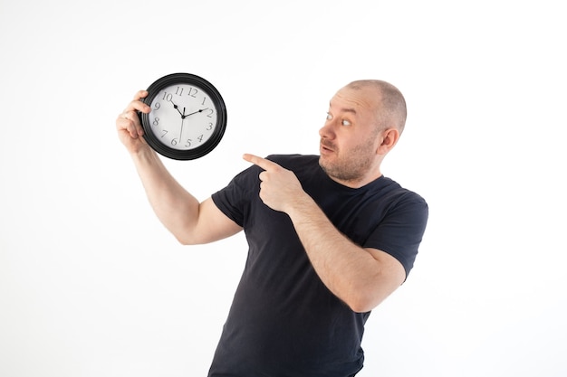 Un hombre con una camiseta sostiene un gran reloj