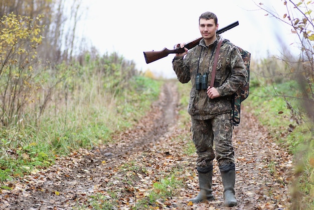 Un hombre de camuflaje y con armas de fuego en un cinturón forestal en una caza de primavera