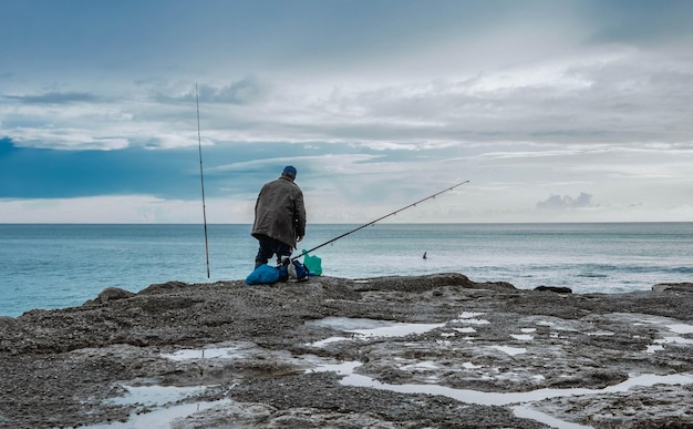 Hombre con caña de pescar en la costa
