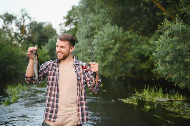 Hombre con caña de pescar hombres pescadores en el agua del río al aire libre Pescando truchas en la red Pasatiempo de pesca de verano