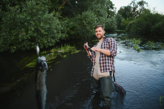 Hombre con caña de pescar hombres pescadores en el agua del río al aire libre Pescando truchas en la red Pasatiempo de pesca de verano