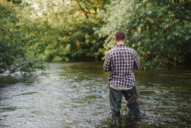 Hombre con caña de pescar hombres pescadores en el agua del río al aire libre Pescando truchas en la red Pasatiempo de pesca de verano