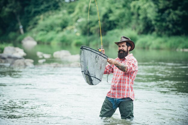 Foto hombre con caña de pescar hombres pescadores en el agua del río al aire libre pescando truchas en la red pasatiempo de pesca de verano