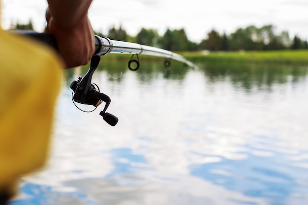 Un hombre con una caña de pescar en la orilla del río está pescando.