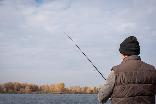 Un hombre con una caña de pescar pescando en el fondo del río Concepto de relajación de pesca