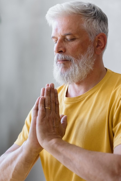 El hombre con canas medita y hace ejercicios de respiración, fitness deportivo y ejercicios físicos para ancianos.