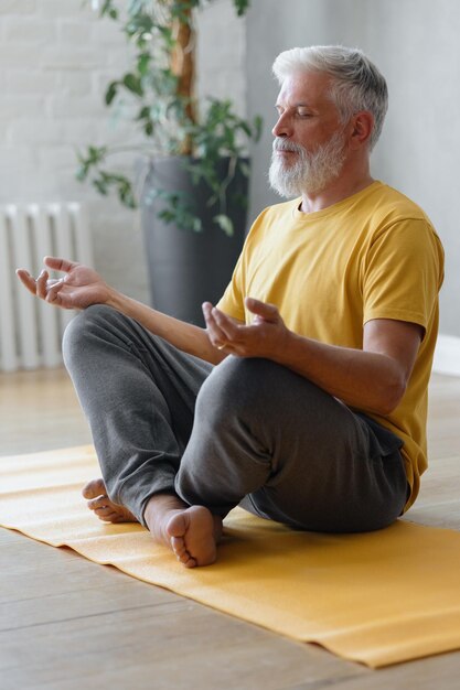 El hombre con canas medita y hace ejercicios de respiración, fitness deportivo y ejercicios físicos para