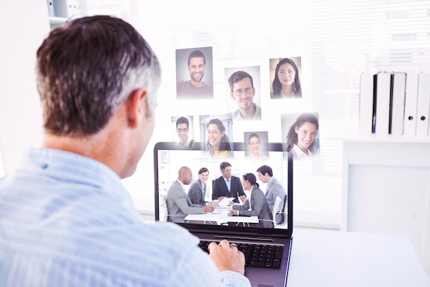 Foto hombre con canas usando su computadora portátil contra gente de negocios discutiendo un plan presupuestario