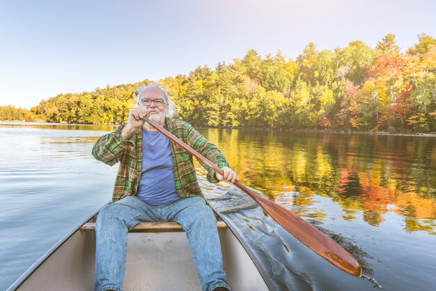 Foto hombre con canoa en el lago en un soleado día de otoño