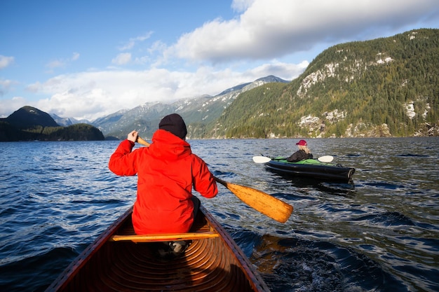 El hombre en una canoa de madera está remando durante un ventoso día de invierno