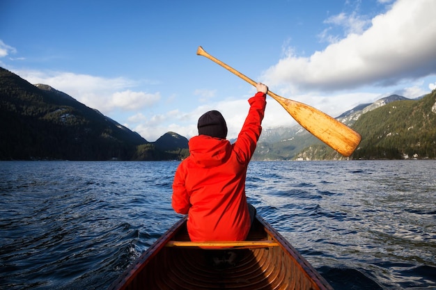 El hombre en una canoa de madera sostiene su remo en el aire