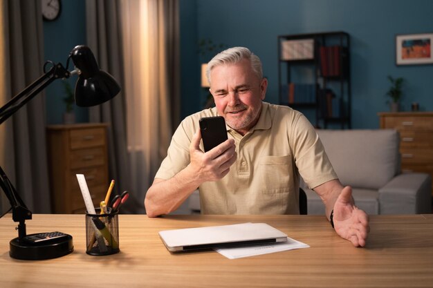 Hombre canoso aprende a usar un teléfono anciano se familiariza con su nuevo teléfono inteligente