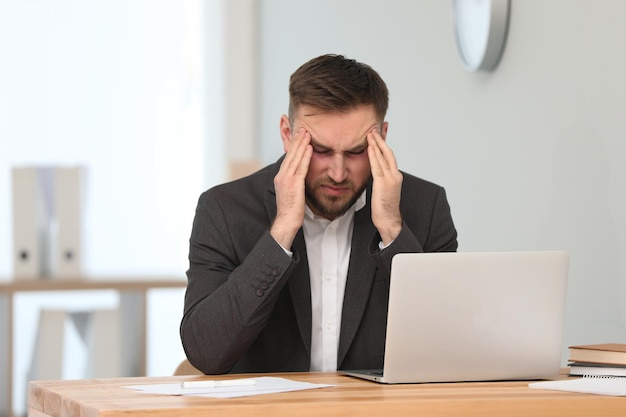 Hombre cansado con ojos rojos en el lugar de trabajo en la oficina