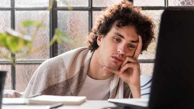 Hombre cansado que trabaja en la computadora portátil