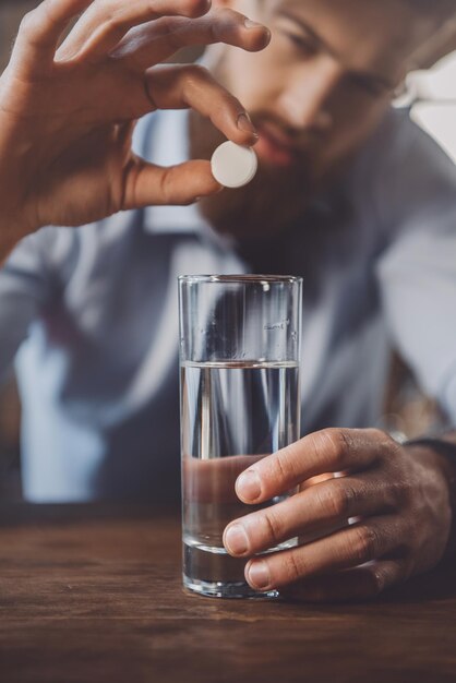 Hombre cansado con resaca con medicamentos después de la fiesta en casa