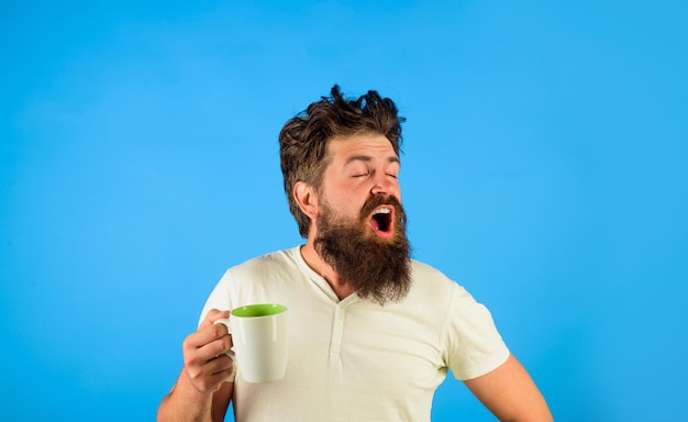 Hombre cansado sostenga la taza de café hombre bostezo sostenga la taza con bebida caliente refresco matutino hombre soñoliento sostiene