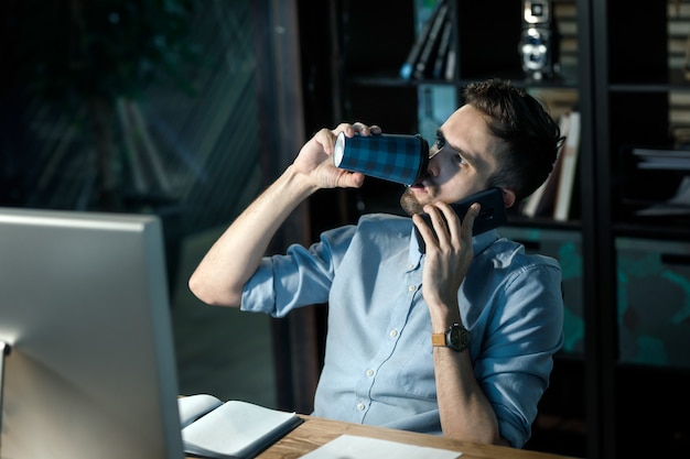 Hombre cansado tomando café en horas extras