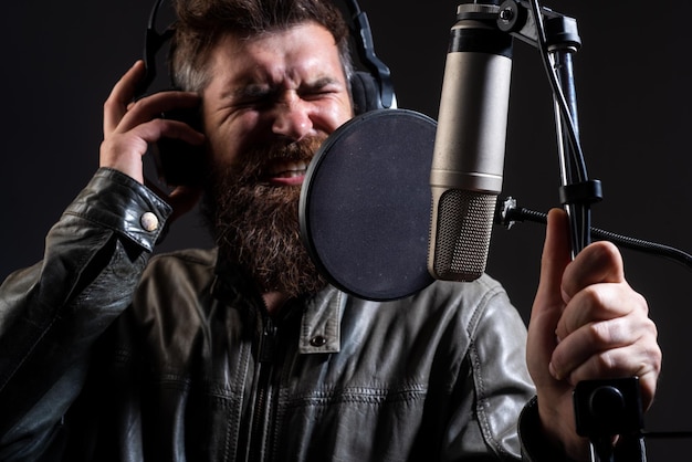 Hombre cantando en un estudio de grabación expresivo hombre barbudo con micrófono karaoke firmante musical voca...