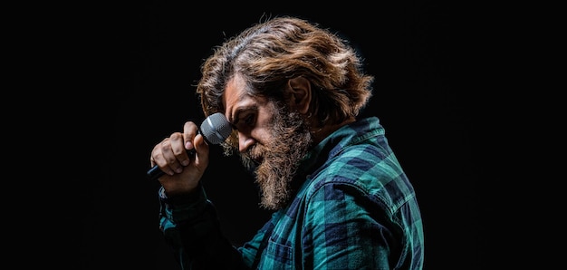 Hombre cantando con un micrófono Hombre con barba sosteniendo un micrófono y cantando