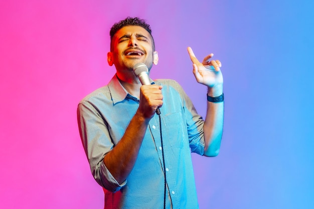 Foto hombre cantando en voz alta la canción sosteniendo el micrófono en la mano divirtiéndose descansando en la actuación del cantante de karaoke