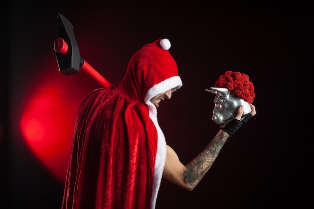 Foto un hombre con una capa roja de papá noel con un hacha y una figura de toro de metal símbolo del nuevo año 2021