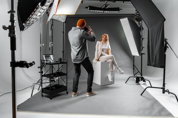 Foto un hombre está capturando a una mujer posando en un cubo en un edificio de estudio fotográfico celebrando un evento con