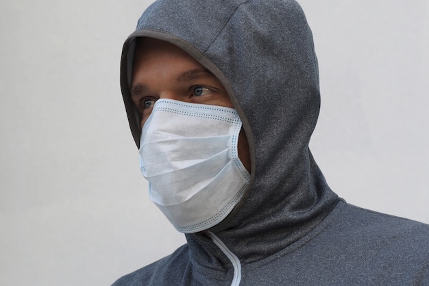 Un hombre con capucha gris con una máscara en la calle. Protección contra virus y gripe.