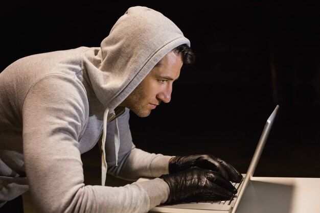 Hombre con capucha pirateando una computadora portátil