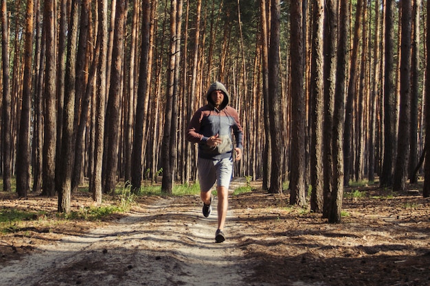 Hombre con capucha tiene entrenamiento en un bosque de pinos