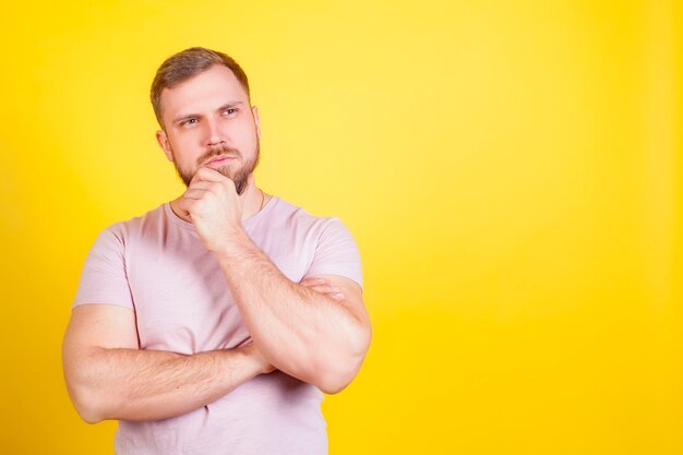 Un hombre con una cara inquisitiva y pensativa, sobre un fondo amarillo Yak. El concepto de toma de decisiones, preguntas en la cabeza.