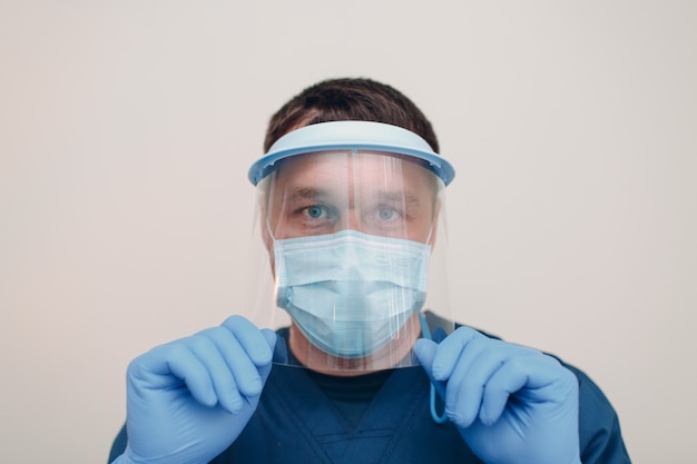 Hombre en la cara máscara quirúrgica médica con máscara de escudo transparente y guantes.