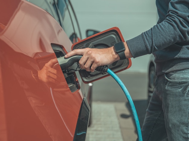 El hombre carga el auto eléctrico en la estación de carga