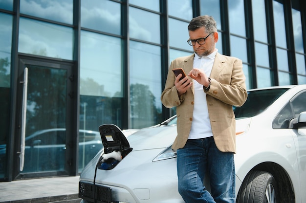 El hombre carga un coche eléctrico en la estación de carga