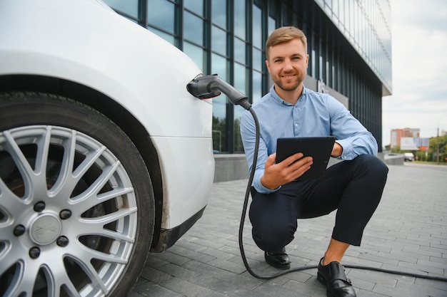 El hombre carga un coche eléctrico en la estación de carga