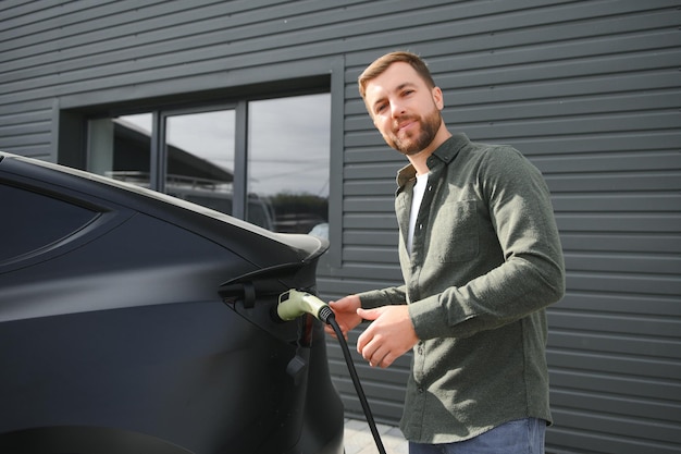 un hombre carga un coche eléctrico