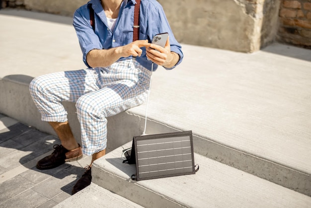 El hombre carga el teléfono desde un panel solar portátil