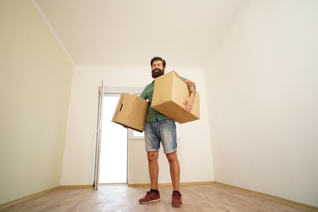 Foto hombre cargando caja de cartón el día de la mudanza repartidor cargando cajas de cartón para mudarse a un departamento