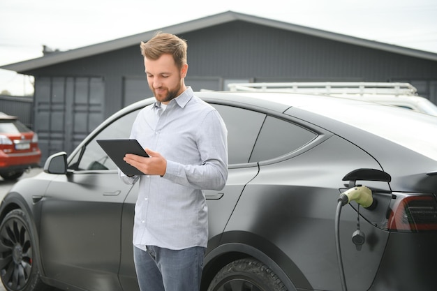 Hombre cargando coche eléctrico por la casa