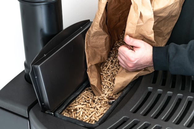 Hombre cargando estufa de pellets con bolsa de gránulos