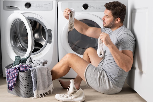 Hombre cargando ropa en la lavadora en el cuarto de lavado hombre de mediana edad poniendo ropa en el lavado