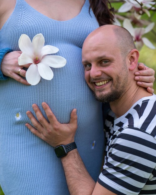 Foto un hombre cariñoso pone su oído en el vientre de su esposa embarazada y escucha los latidos del corazón del bebé