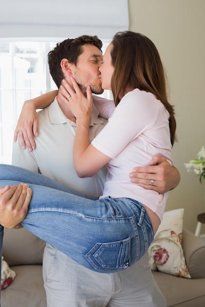 Hombre cariñoso que lleva a la mujer mientras la besa