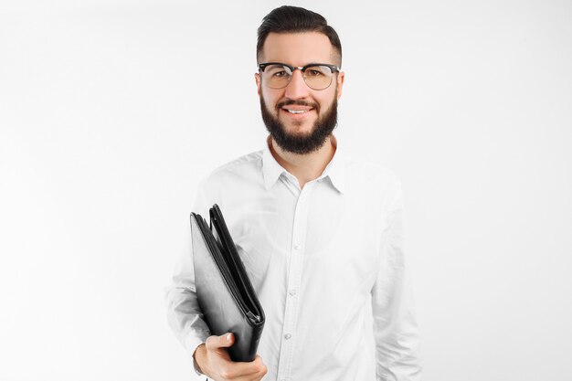 Hombre con una carpeta en sus manos, sobre una pared blanca, empresario con gafas