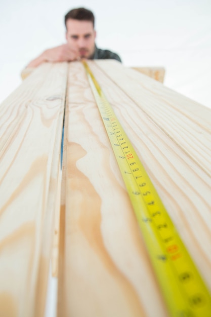 Foto hombre carpintero que mide el tablón de madera