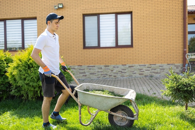 Hombre con carretilla de hierba recién cortada