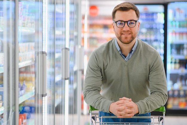 Un hombre con un carro camina en un supermercado