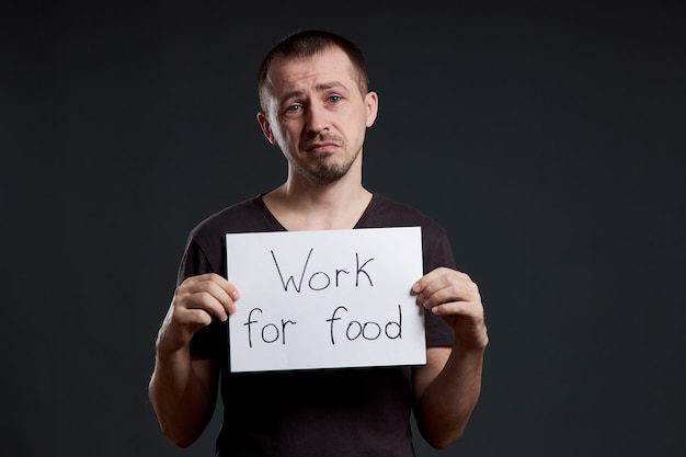 Hombre con un cartel con las palabras trabajar por comida