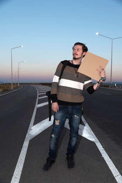 Foto hombre con cartón de pie en la carretera contra el cielo