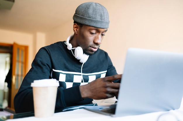 Hombre en casa con teléfono inteligente y computadora portátil